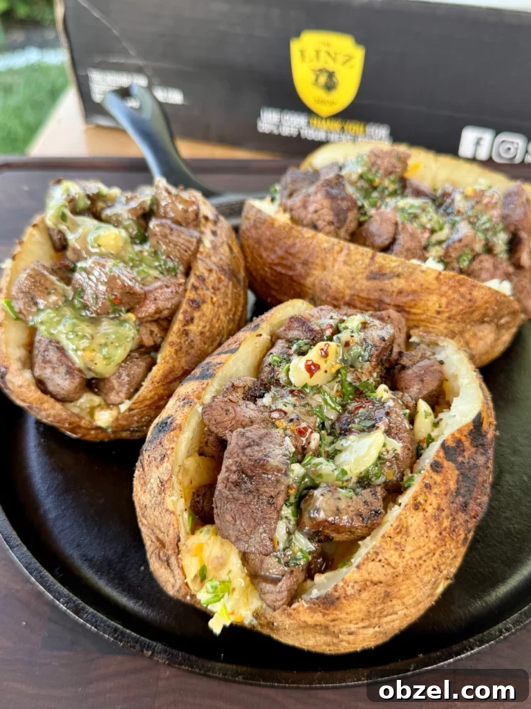 Loaded Baked Potatoes with Grilled Steak Bites 2 Completed grilled steak bite loaded baked potatoes garnished with fresh chives and drizzled with garlic herb butter on serving plates