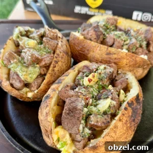 Loaded Baked Potatoes with Grilled Steak Bites 12 Completed grilled steak bite loaded baked potatoes garnished with fresh chives and drizzled with garlic herb butter on serving plates