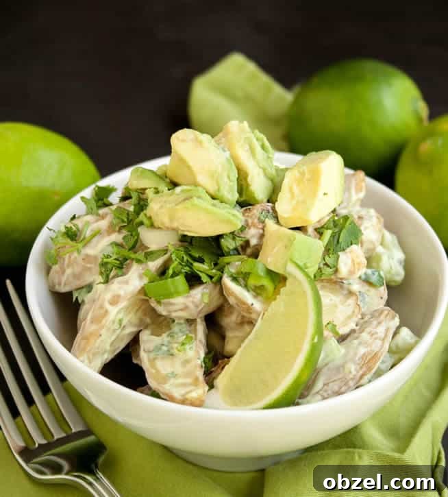Roasted Potato Salad with Avocado Lime Dressing in a bowl topped with avocado and slice of lime from themerchantbaker.com