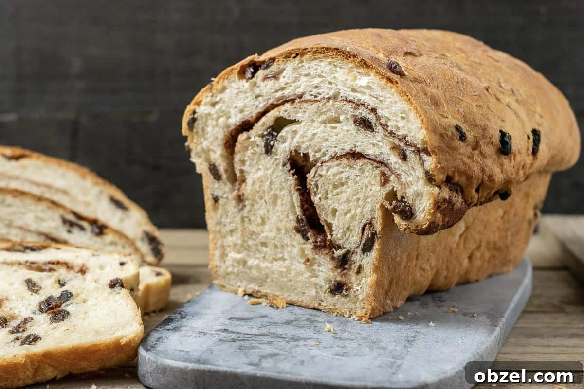 Cinnamon Raisin Swirl Bread Recipe 10 Raisin swirl bread on a cutting board with three slices laying down.