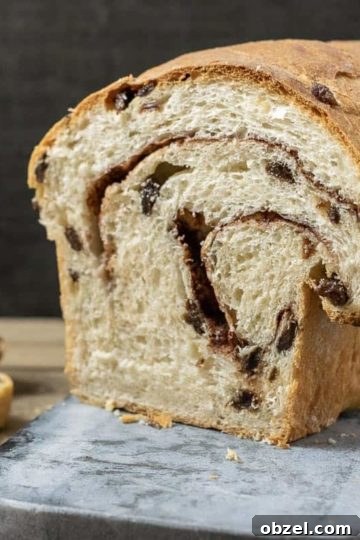 Cinnamon Raisin Swirl Bread Recipe 11 Homemade cinnamon swirl raisin bread on a cutting board with three slices.