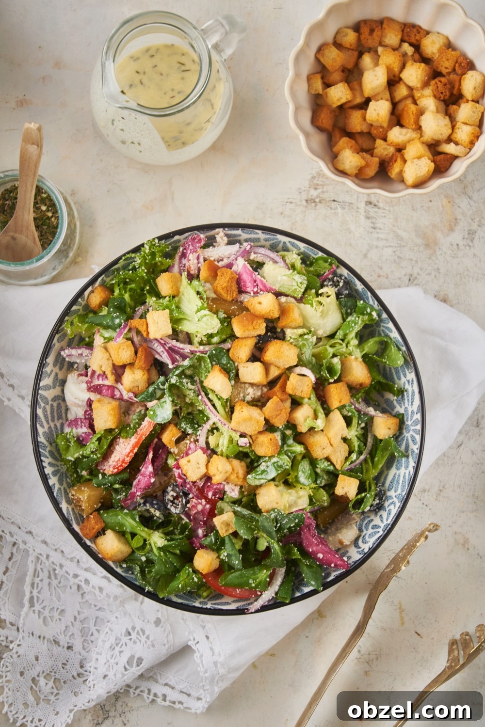 Olive Garden Salad Recipe with Homemade Dressing 2 Overhead view of a salad filled with lettuce, peppers, onions, black olives, parmesan cheese, and croutons.