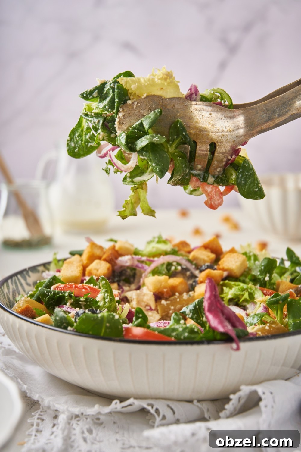 Olive Garden Salad Recipe with Homemade Dressing 4 A set of tongs holding a serving of salad above a large bowl of salad.