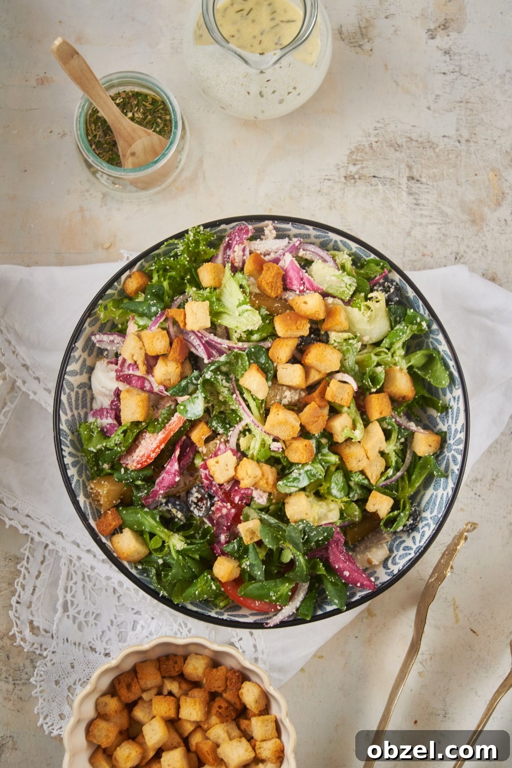 Olive Garden Salad Recipe with Homemade Dressing 8 Overhead view of a salad filled with lettuce, peppers, onions, black olives, parmesan cheese, and croutons.