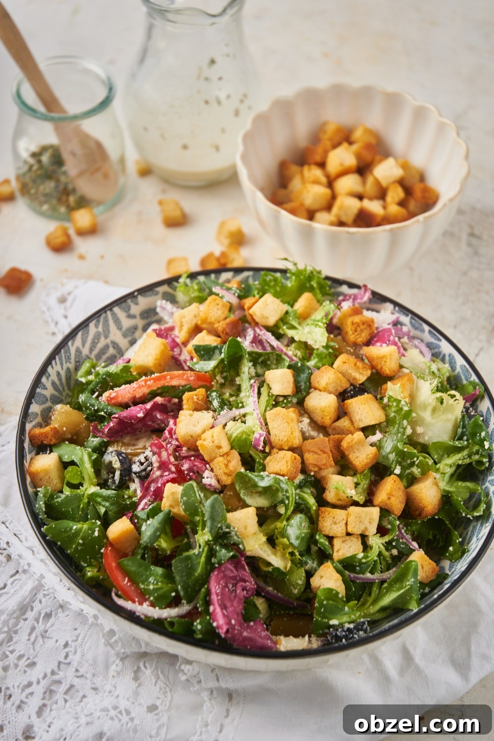 Olive Garden Salad Recipe with Homemade Dressing 9 A large bowl of salad filled with lettuce, peppers, onions, black olives, parmesan cheese, and croutons.