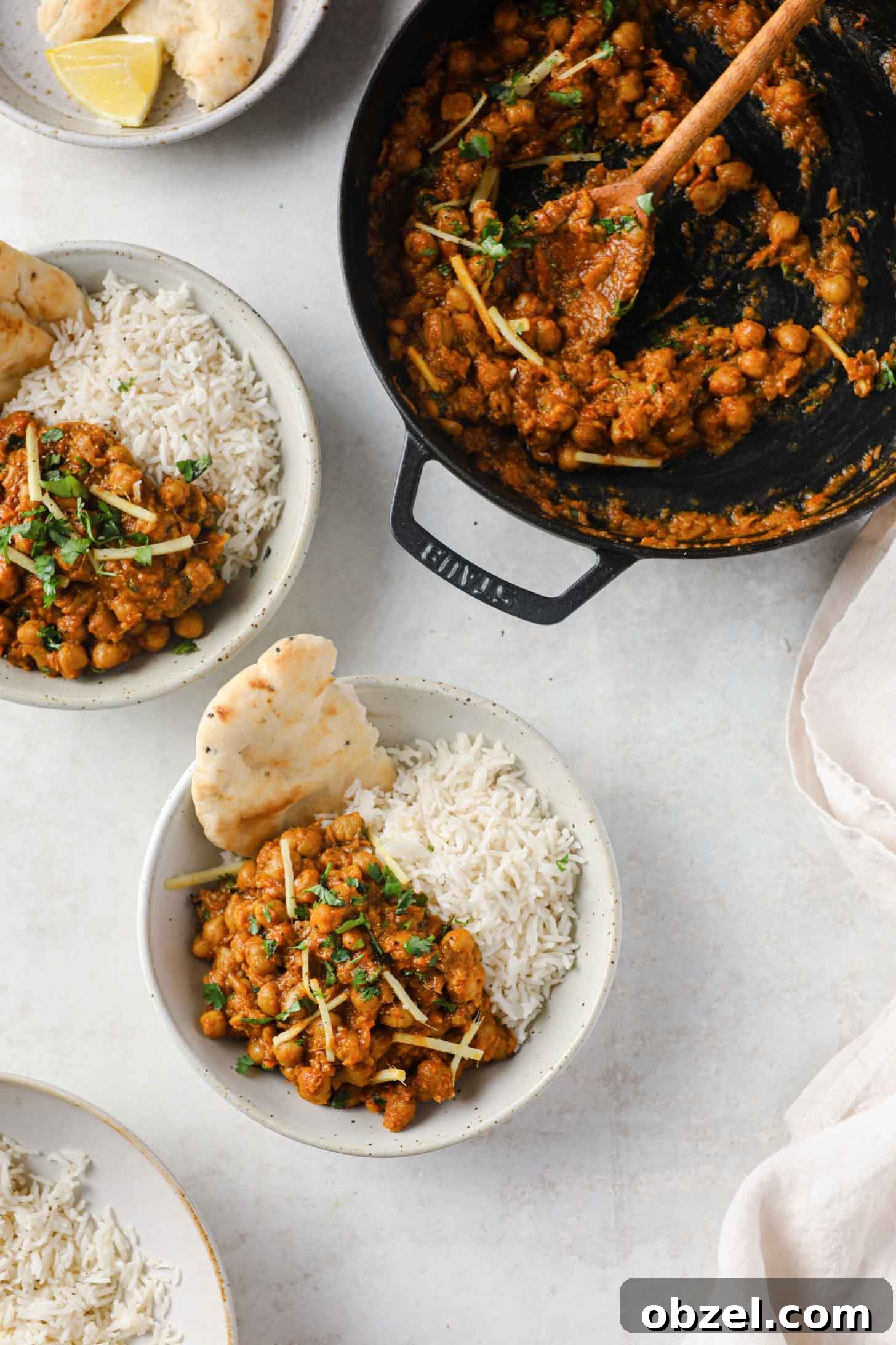 Chana Masala scooped out from a skillet and placed into bowls with basmati rice and naan ready to be eaten