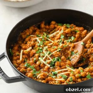 Authentic Chana Masala garnished with cilantro and julienned ginger in a black skillet