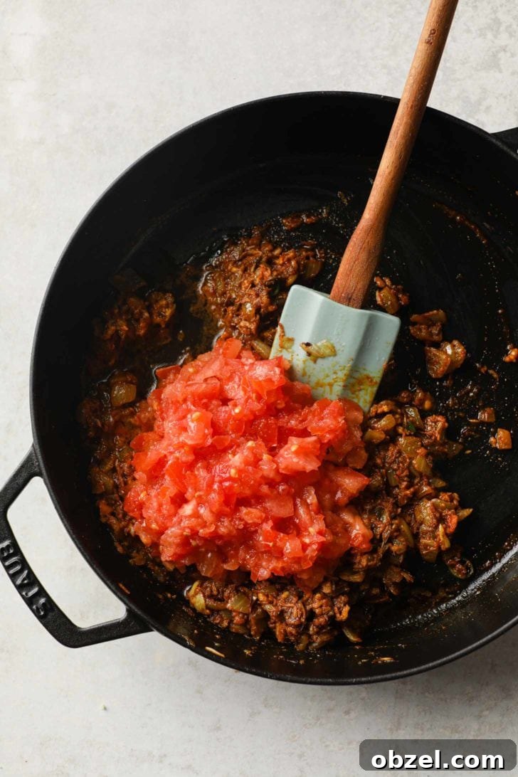 tomatoes added to onion masala in a skillet