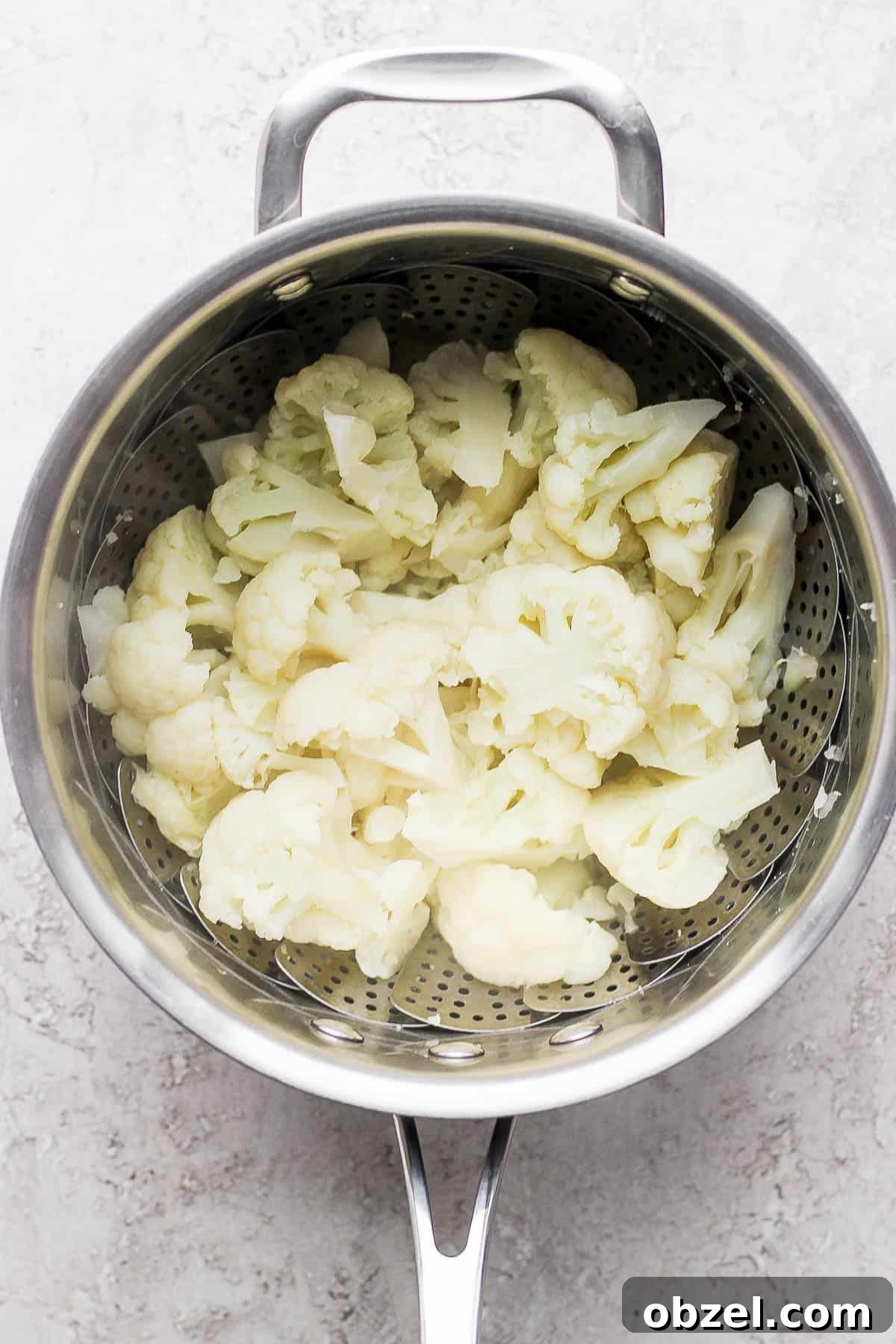 Steamed cauliflower in a steamer basket.