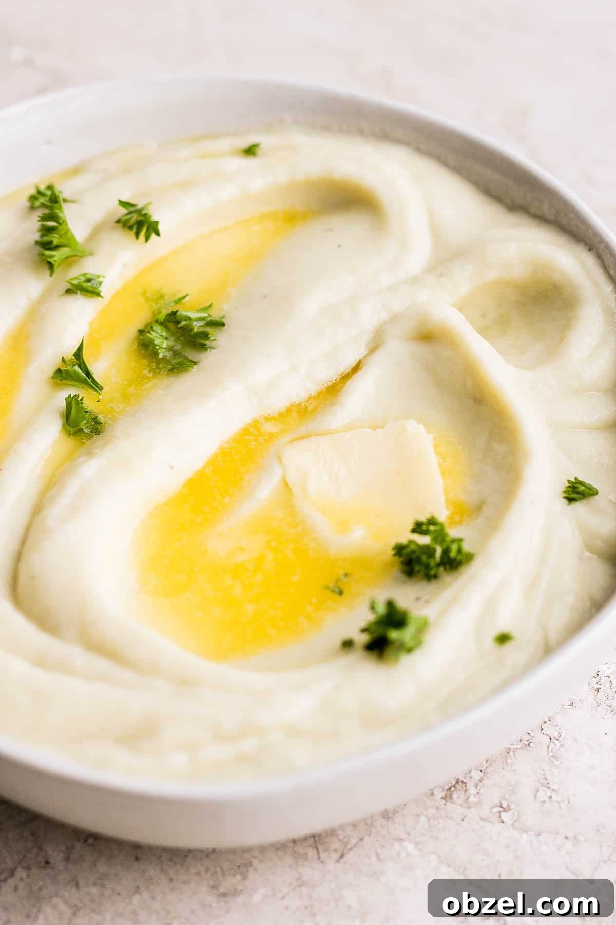 Cauliflower mash in a bowl with butter on top.