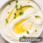Bowl of mashed cauliflower with fresh parsley and melted butter.