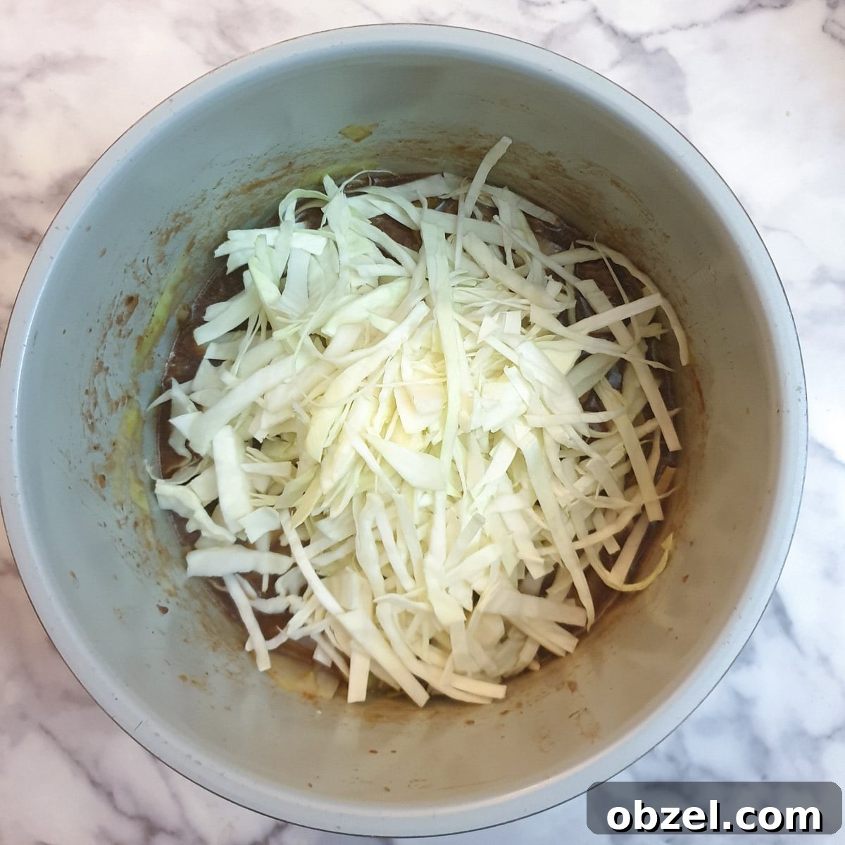 South African Beef Bredie Stew Recipe 9 A pile of shredded raw cabbage on top of beef stew in a pressure cooker.