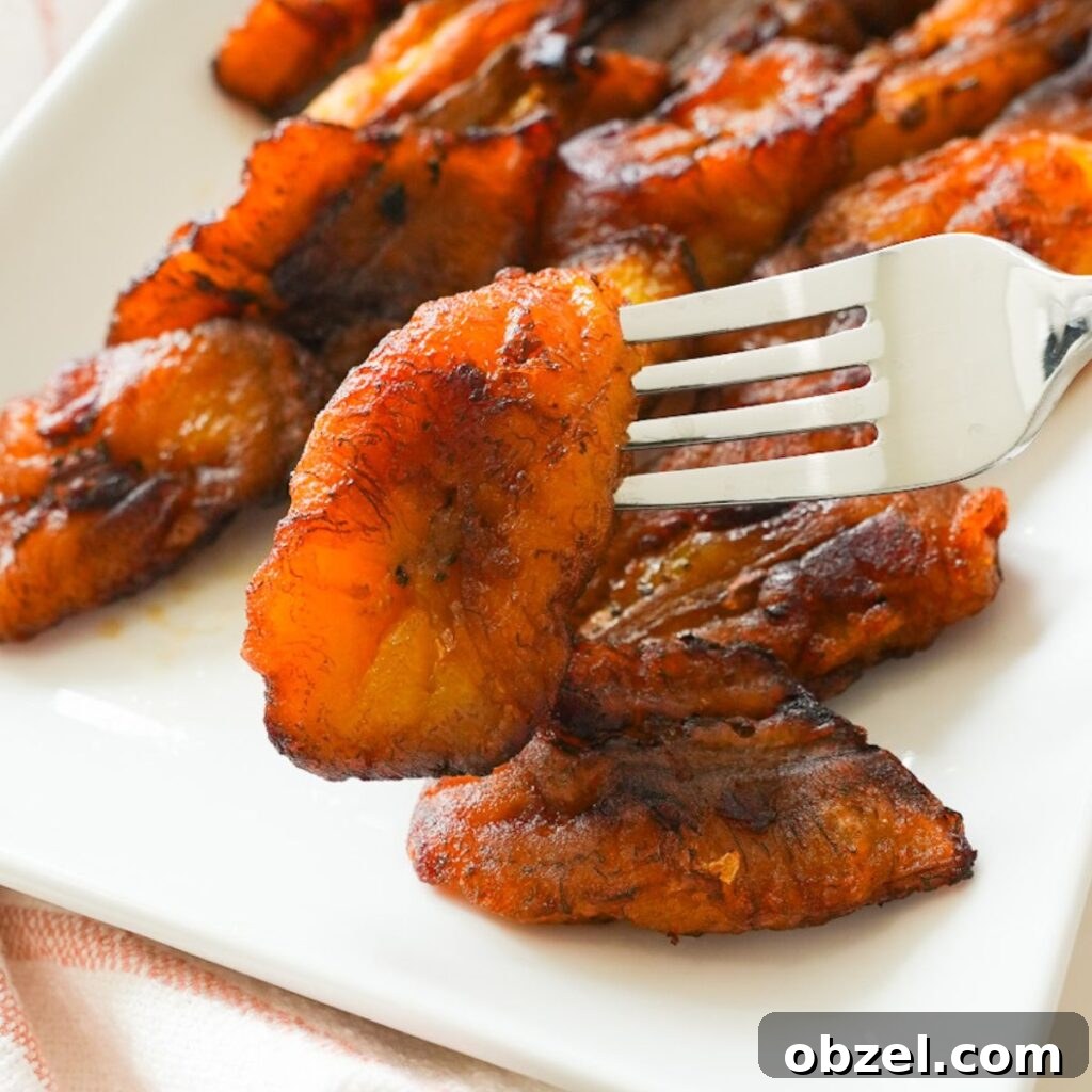 Crispy Fried Maduros (Sweet Plantains Recipe) 4 Close up of fried sweet plantain on a fork.