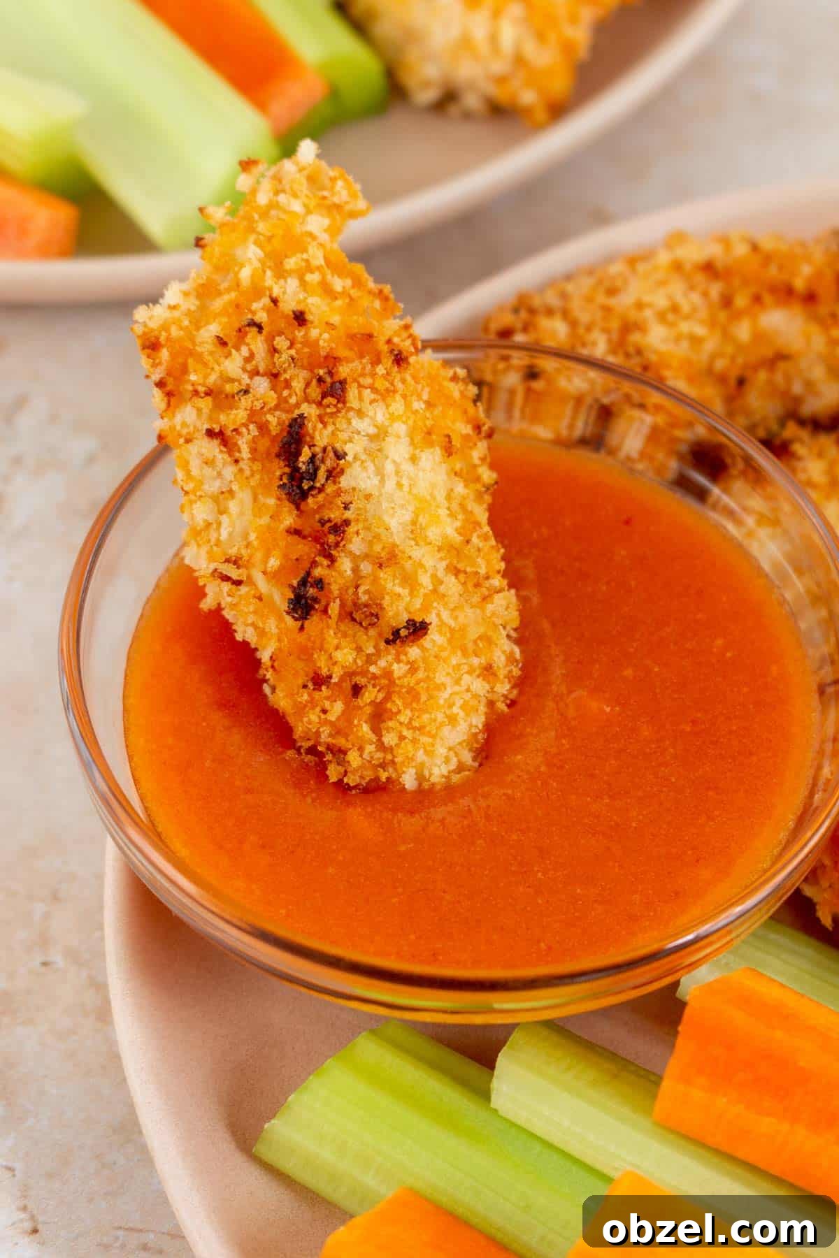 Crispy Air Fryer Buffalo Chicken Tenders 6 An air fryer buffalo chicken tender dipped into a bowl of buffalo sauce.