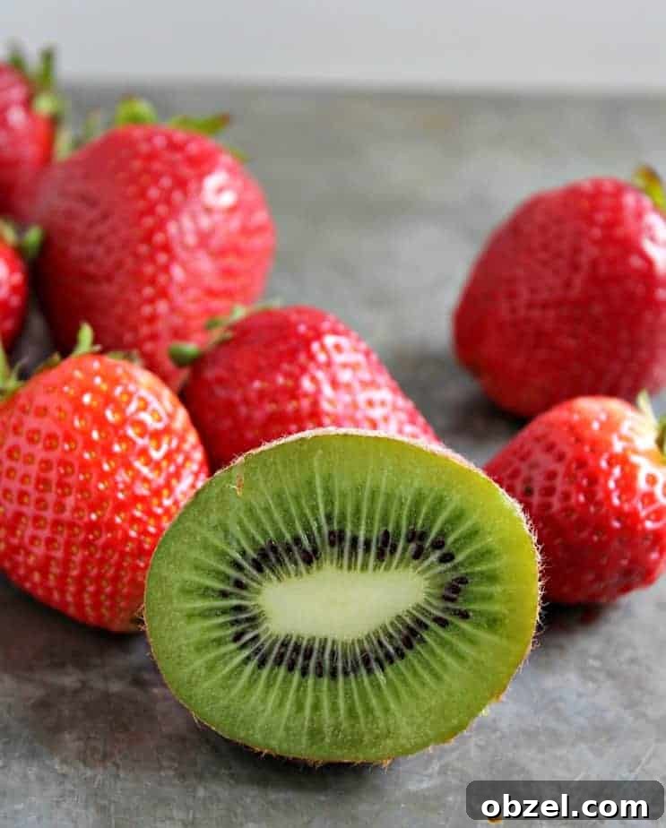 Fresh strawberries and kiwis on a gray surface.