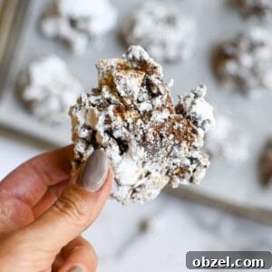 No Bake Muddy Buddy Cookies 14 holding a muddy buddies cookie in front of a baking sheet full of cookies.