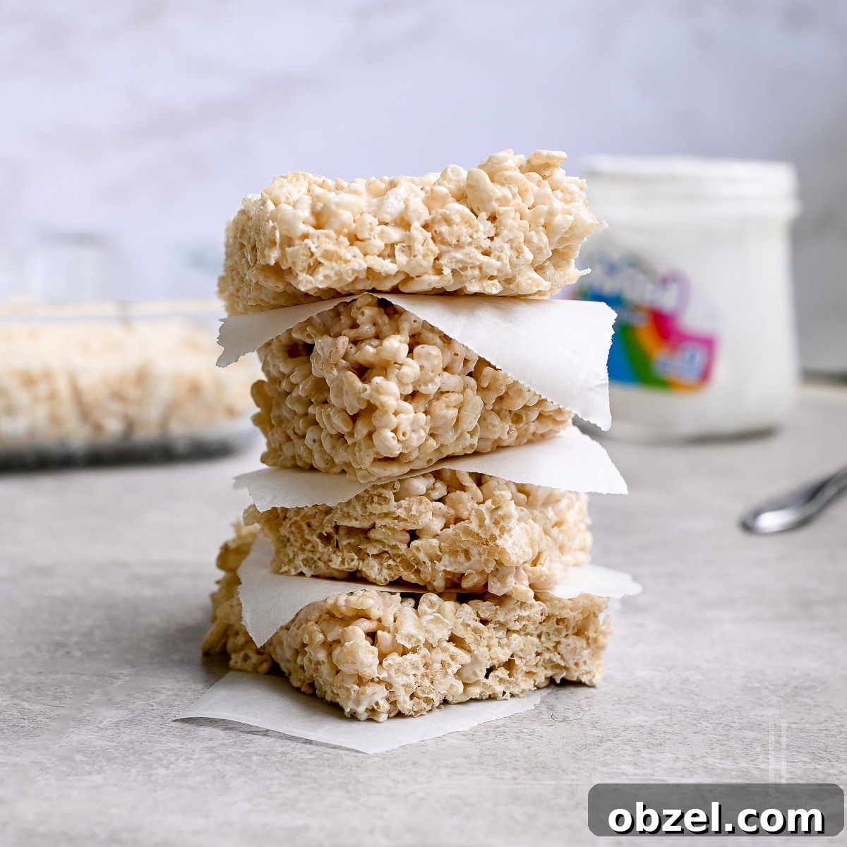 No Bake Muddy Buddy Cookies 9 rice krispie treats stacked in front of a baking dish, marshmallow fluff container.
