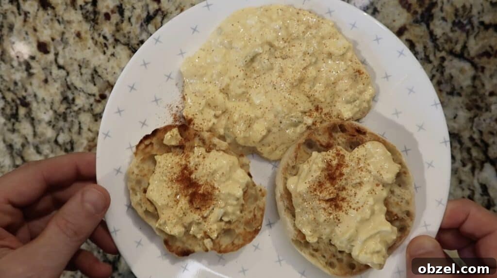 Egg salad on English muffins and on plate with paprika sprinkled on top.