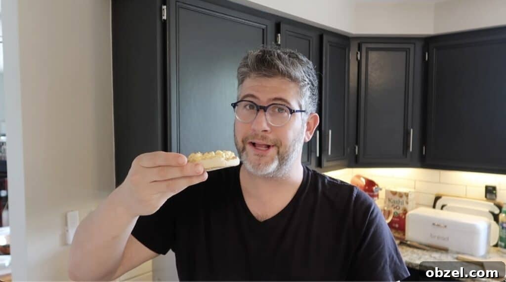 Man smiling while holding English muffin with deviled egg salad on it.