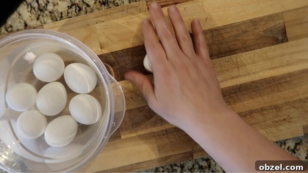 Rolling the egg on a flat surface so the shell fractures