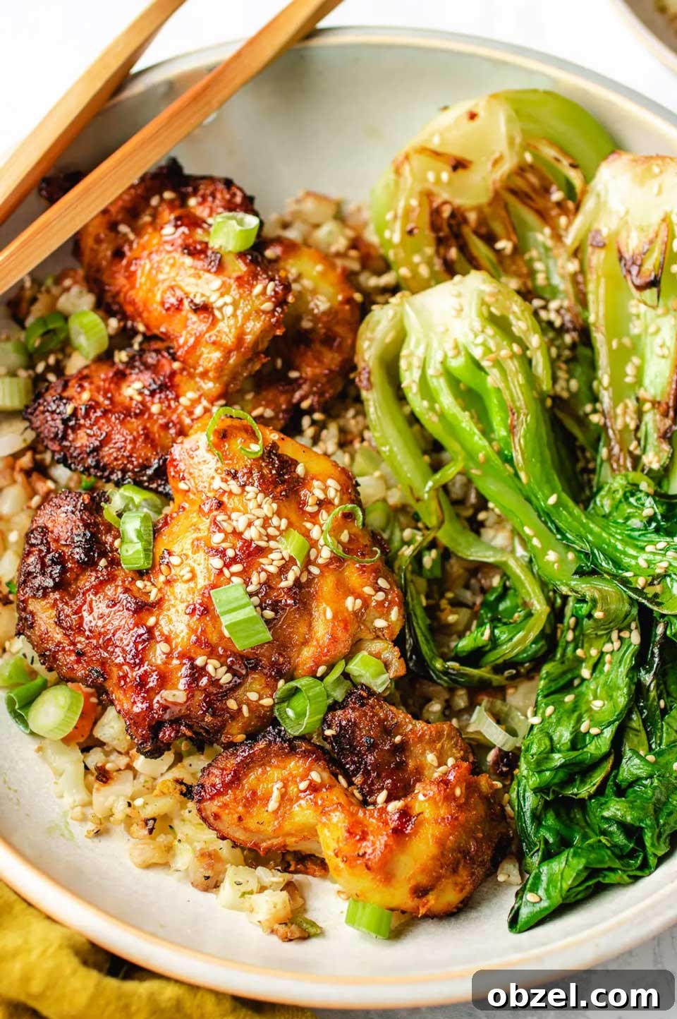 15 Air Fryer Chicken Thigh Recipes for Crispy, Juicy Results 7 Air fried chicken nestled with rice and bok choy, with chopsticks across edge of plate.