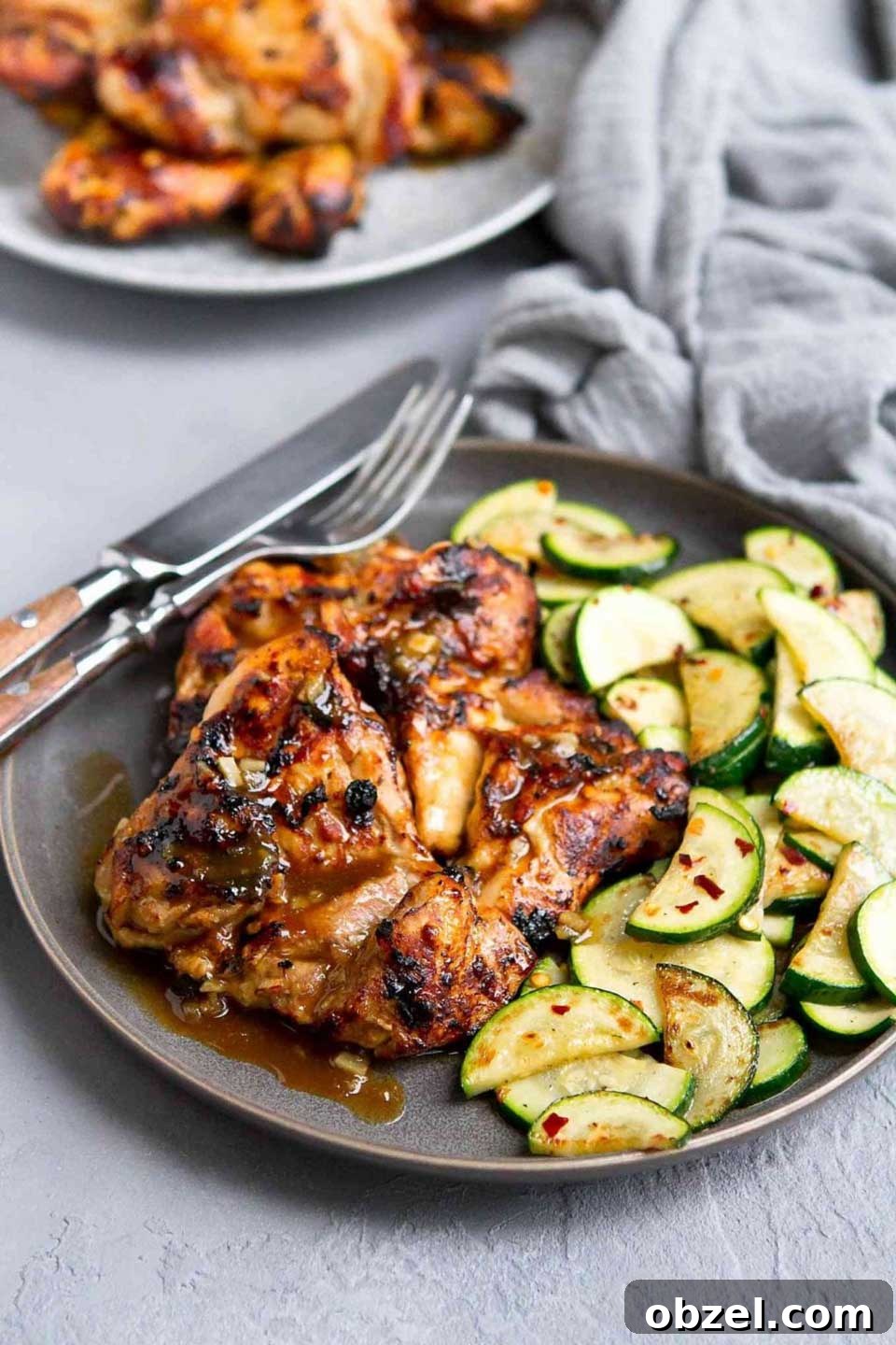 15 Air Fryer Chicken Thigh Recipes for Crispy, Juicy Results 9 Two honey balsamic thighs on gray plate with sauteed zucchini side dish.