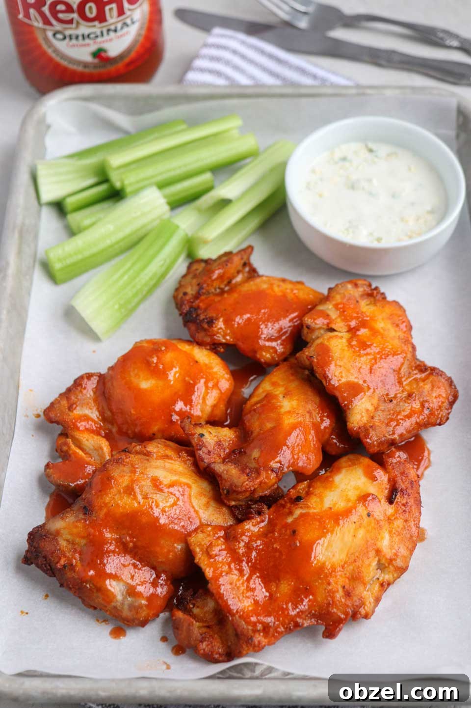 15 Air Fryer Chicken Thigh Recipes for Crispy, Juicy Results 10 Several buffalo chicken pieces on paper-lined tray with ranch and celery sticks.