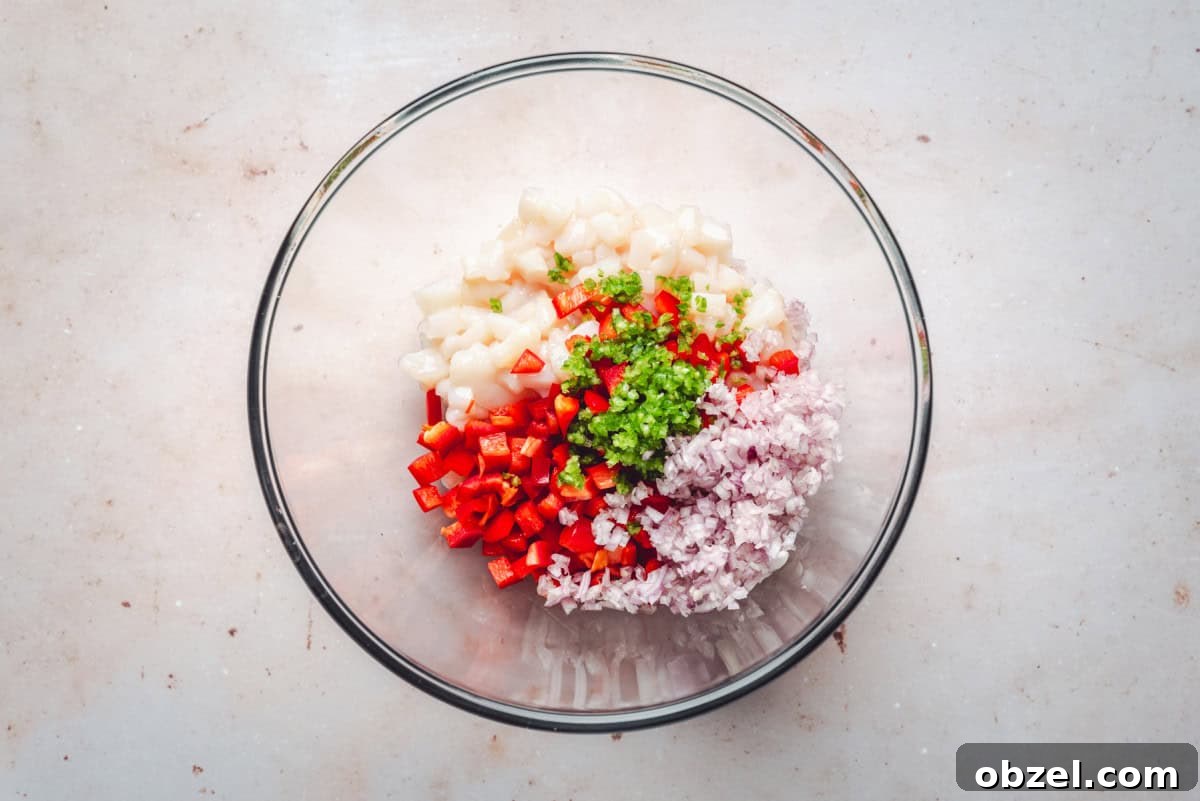 Citrus Scallop Ceviche Recipe with Lime and Fresh Herbs 4 Scallops, red bell pepper, shallot, jalapeño, lemon, lime and orange juices added to a medium glass bowl.