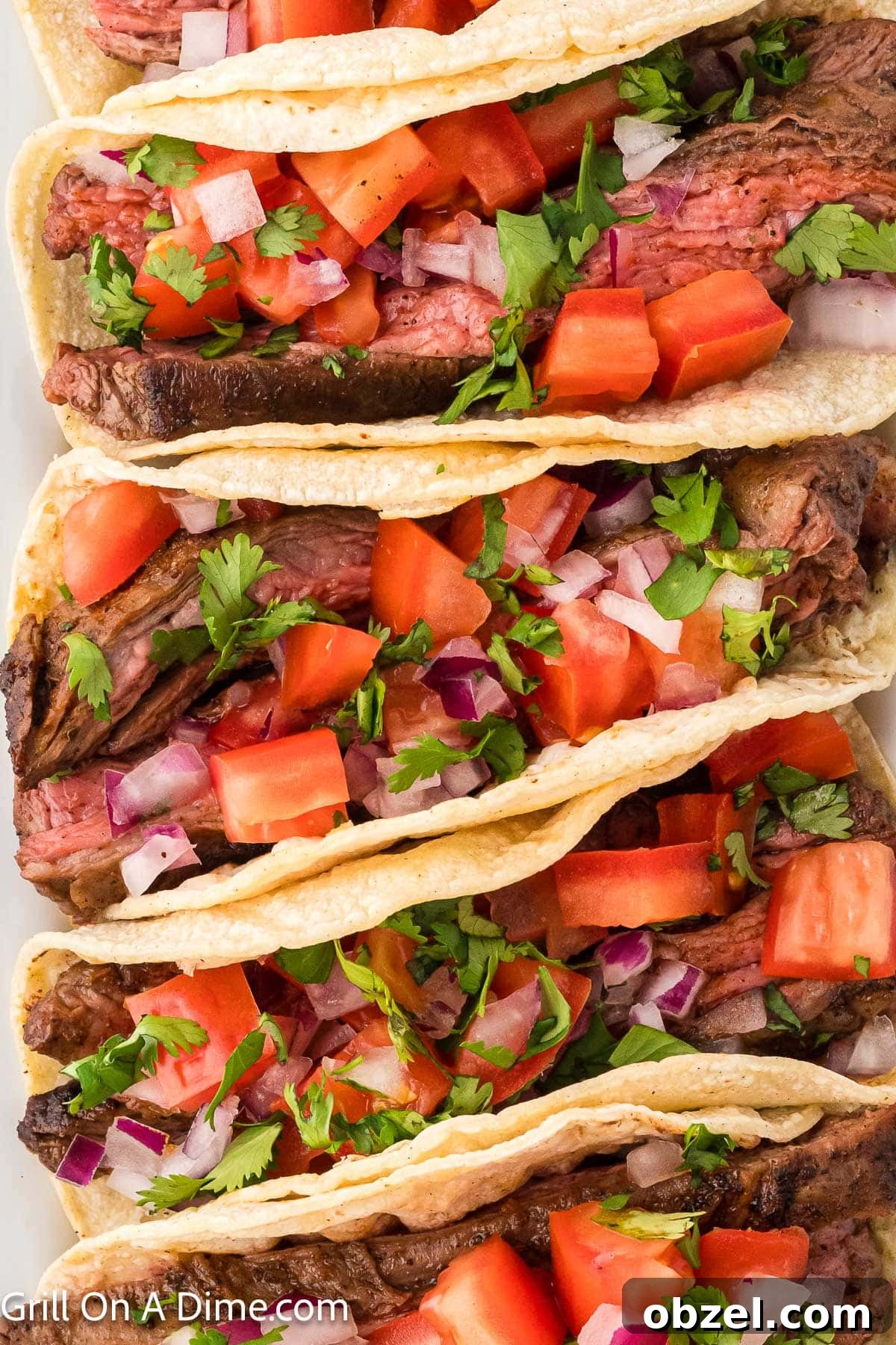 Juicy Blackstone Steak Tacos with Charred Onions and Lime 2 Steak Tacos in a corn tortillas topped with diced tomatoes, red onions and fresh cilantro