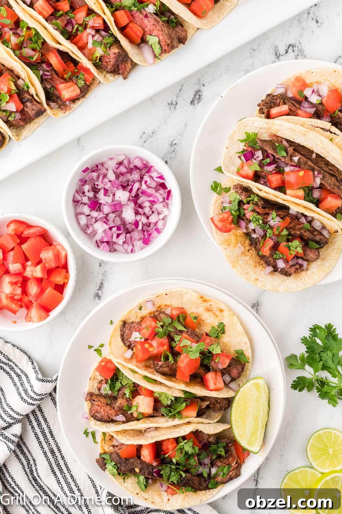 Juicy Blackstone Steak Tacos with Charred Onions and Lime 11 Steak tacos on a white plate with bowl of chopped red onions and diced tomatoes