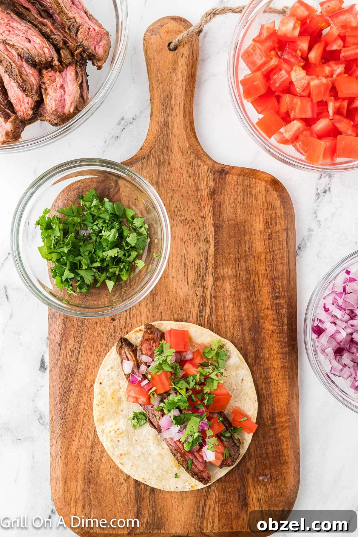 Juicy Blackstone Steak Tacos with Charred Onions and Lime 9 Corn tortillas topped with steak strips with diced tomatoes, fresh cilantro and red onions with a bowl of fresh cilantro on the side