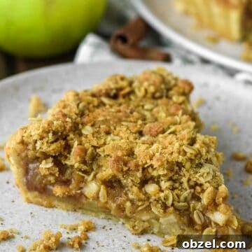 Slice of apple crumble tart on speckled plate.