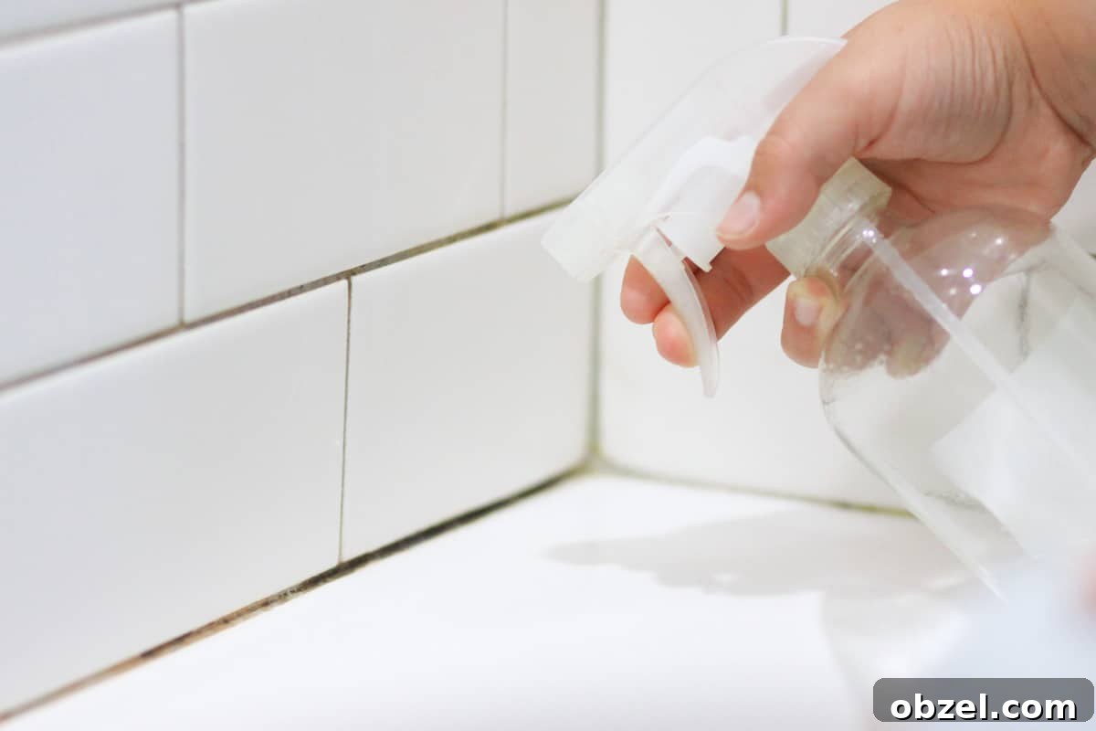 mold in shower tile grout being sprayed with vinegar in a spray bottle