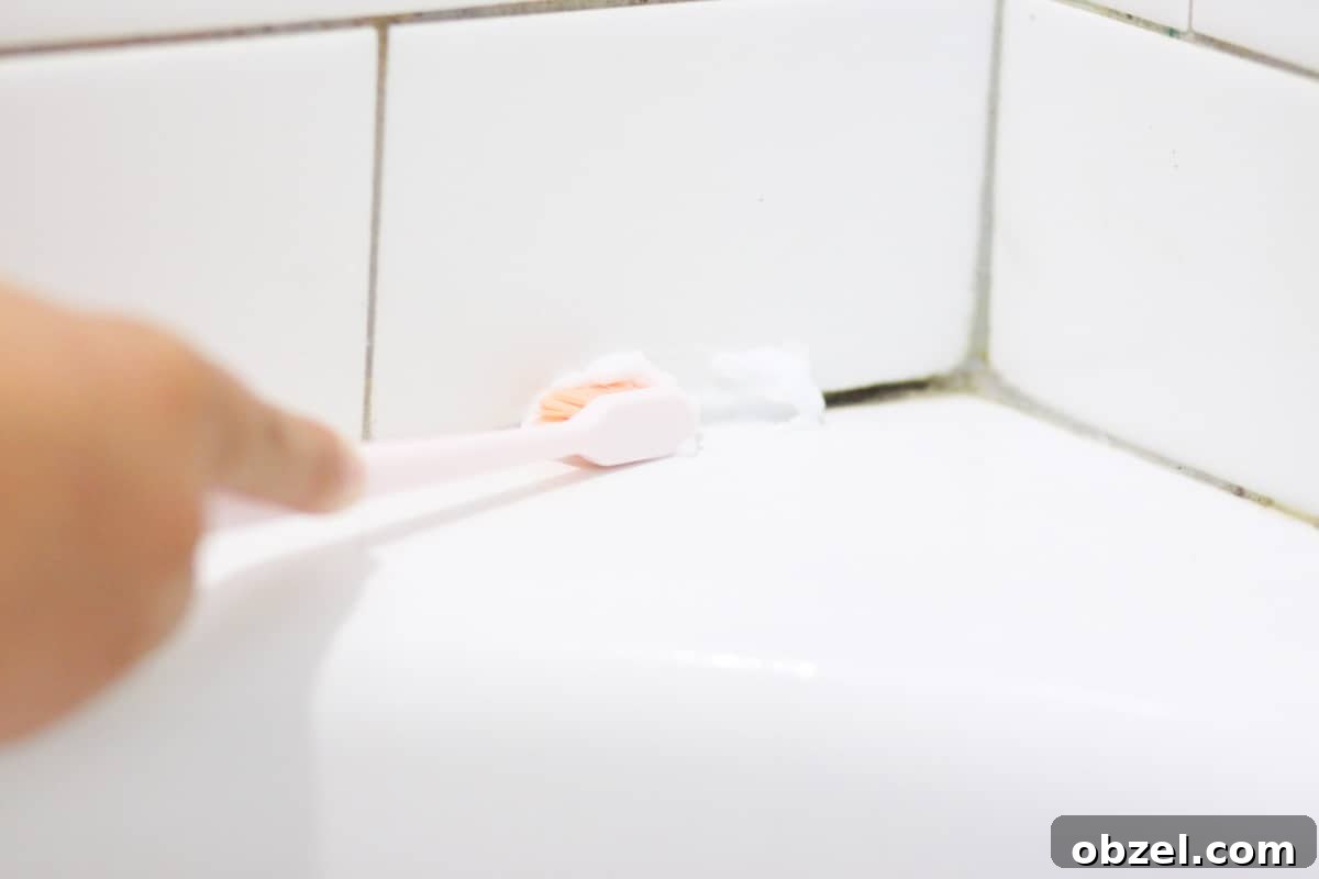 mold in shower tile grout being cleaned with a toothbrush and a baking soda cleaning paste