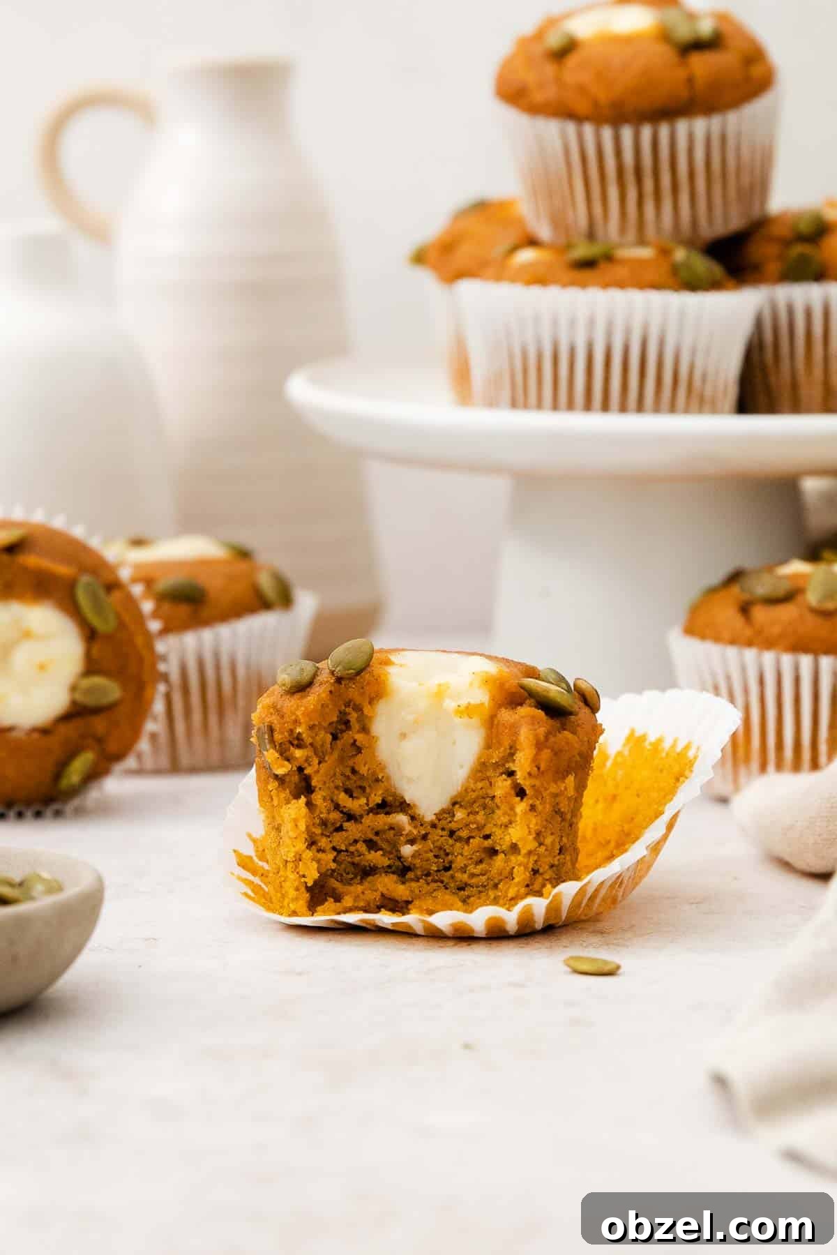 Gluten-free pumpkin cream cheese muffins on a countertop with a bite taken out of one of them.