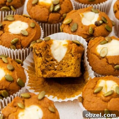 Gluten-free pumpkin cream cheese muffins on a countertop with a bite taken out of one of them.