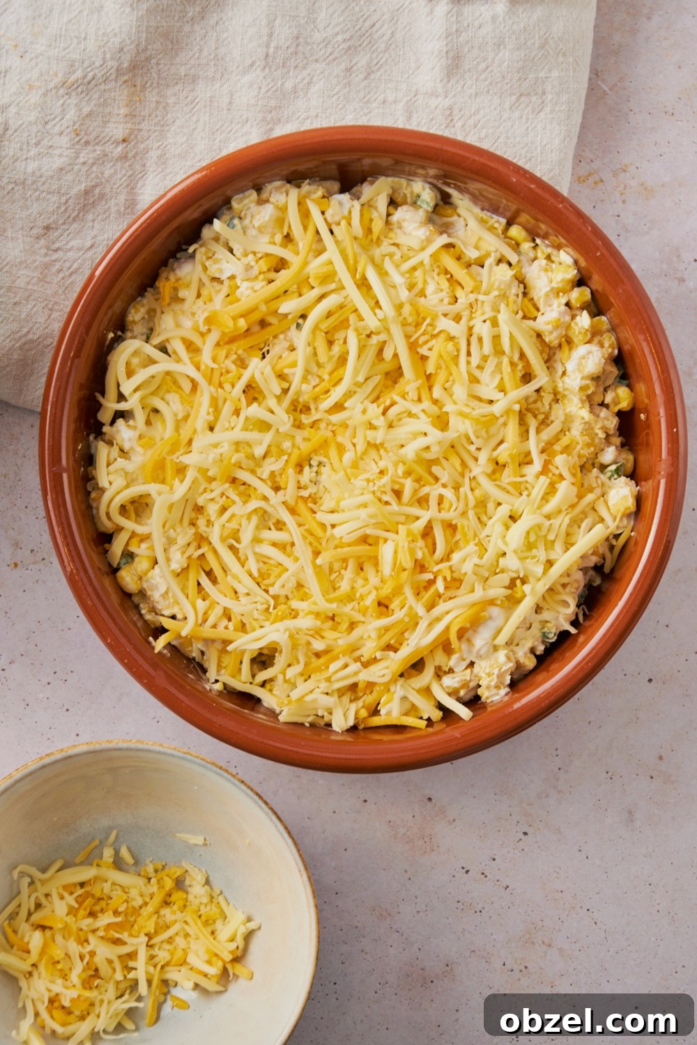 Jalapeno Corn Casserole with Cheddar 6 Shredded cheese on top of a jalapeno corn casserole in a red dish
