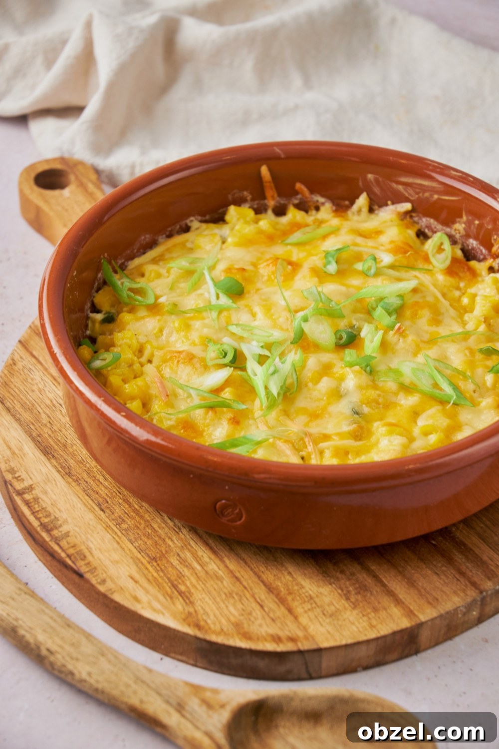 Jalapeno Corn Casserole with Cheddar 8 A red dish of cooked jalapeno corn casserole on a wooden serving platter