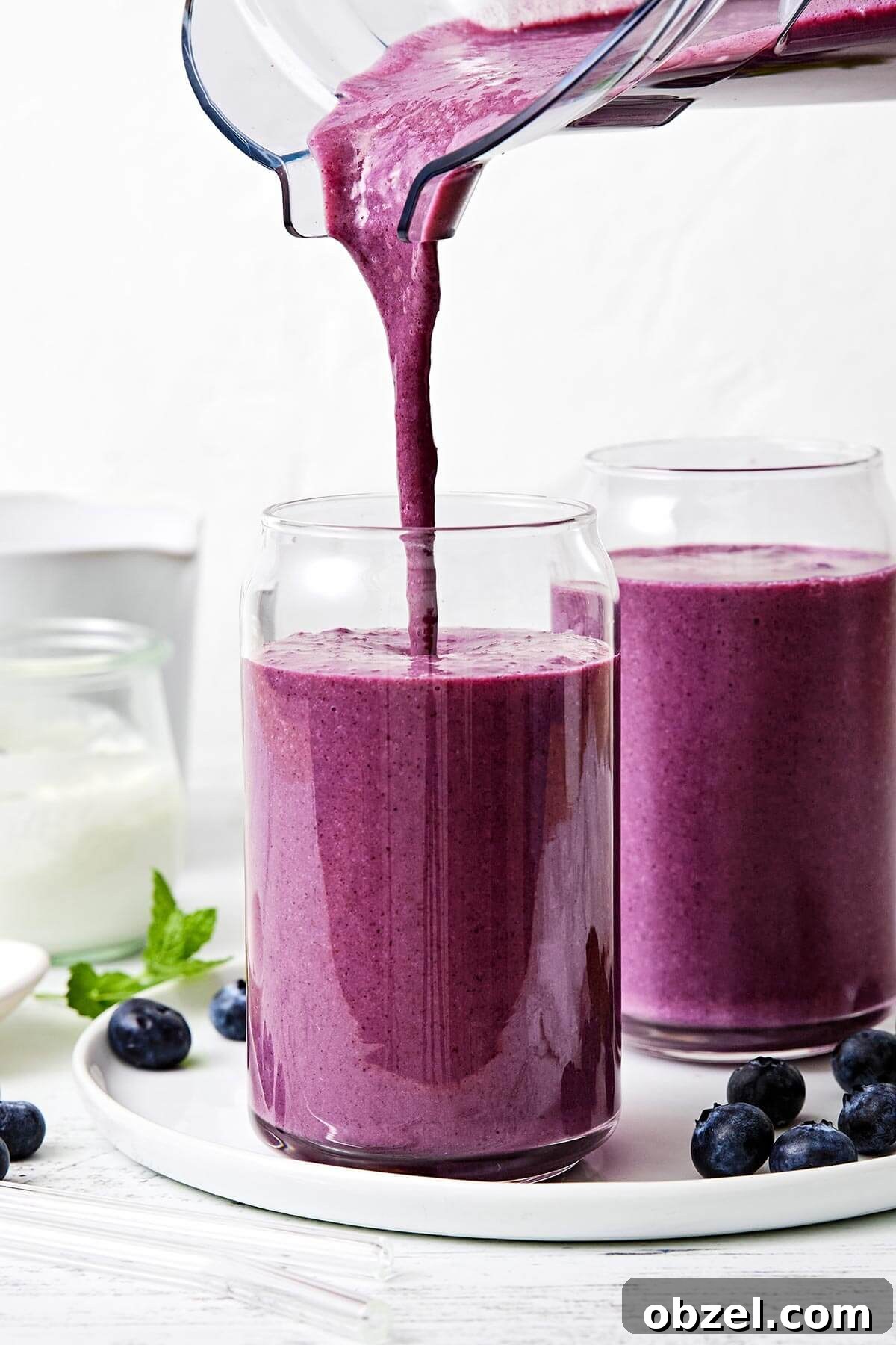 Pouring blueberry smoothie into a cup.