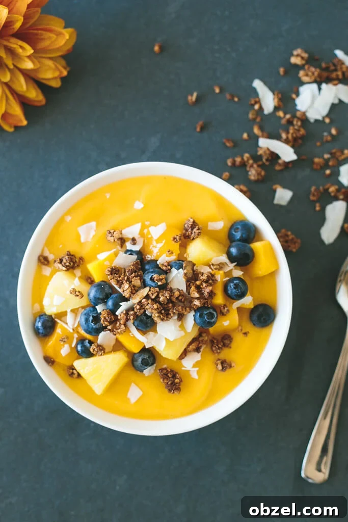 (gluten-free) Mango Smoothie Bowl. The perfect summer smoothie bowl, filled with mangoes, pineapple, blueberries and gluten-free granola.