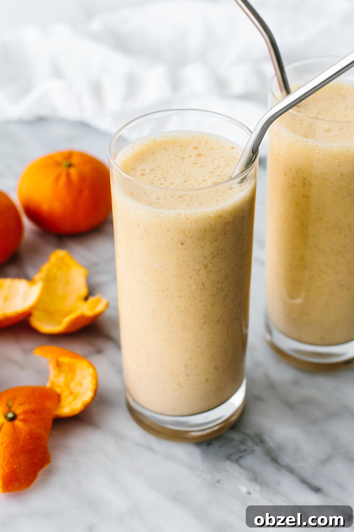 Mandarin breakfast smoothie in a glass next to mandarin oranges.