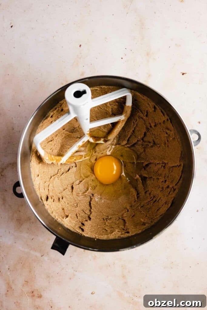 Adding eggs one by one to beaten butter and oil