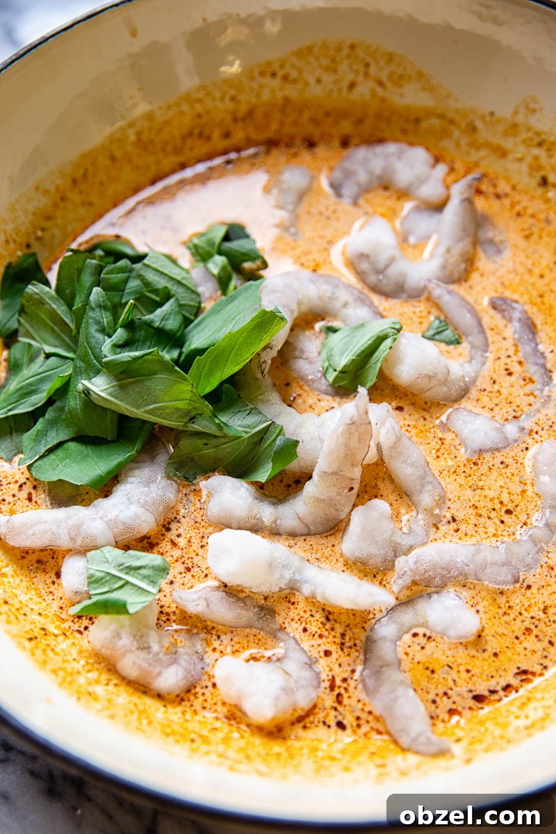 Prawns in creamy sun-dried tomato sauce with fresh basil in white pan
