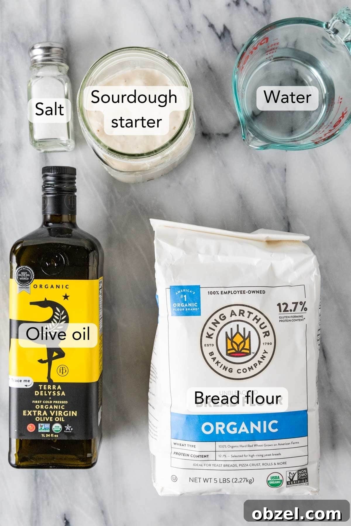 Homemade Sourdough Bread Recipe with Starter 3 Overhead view of ingredients needed for the sourdough bread recipe including olive oil, bread flour, sourdough starter, and more.