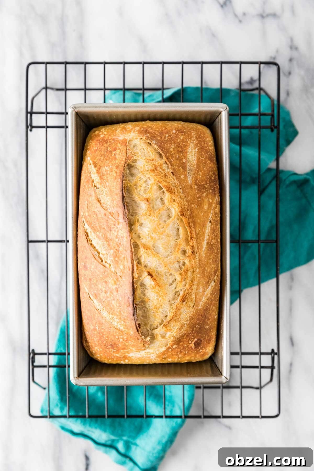 Homemade Sourdough Bread Recipe with Starter 10 Overhead view of a loaf of homemade bread in a bread pan on a cooling rack.