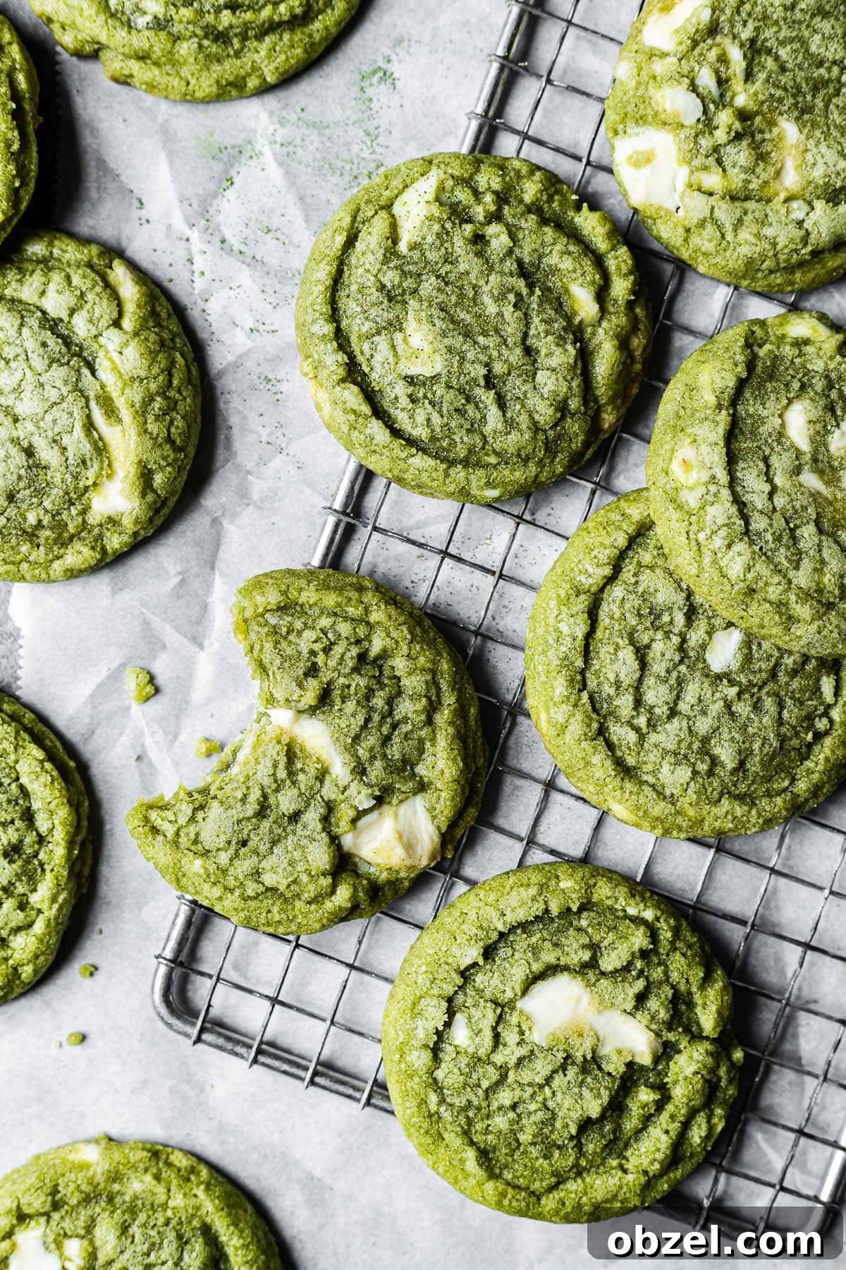 Matcha White Chocolate Cookies Recipe 2 Matcha cookies on a metal wire cooling rack and white parchment paper.