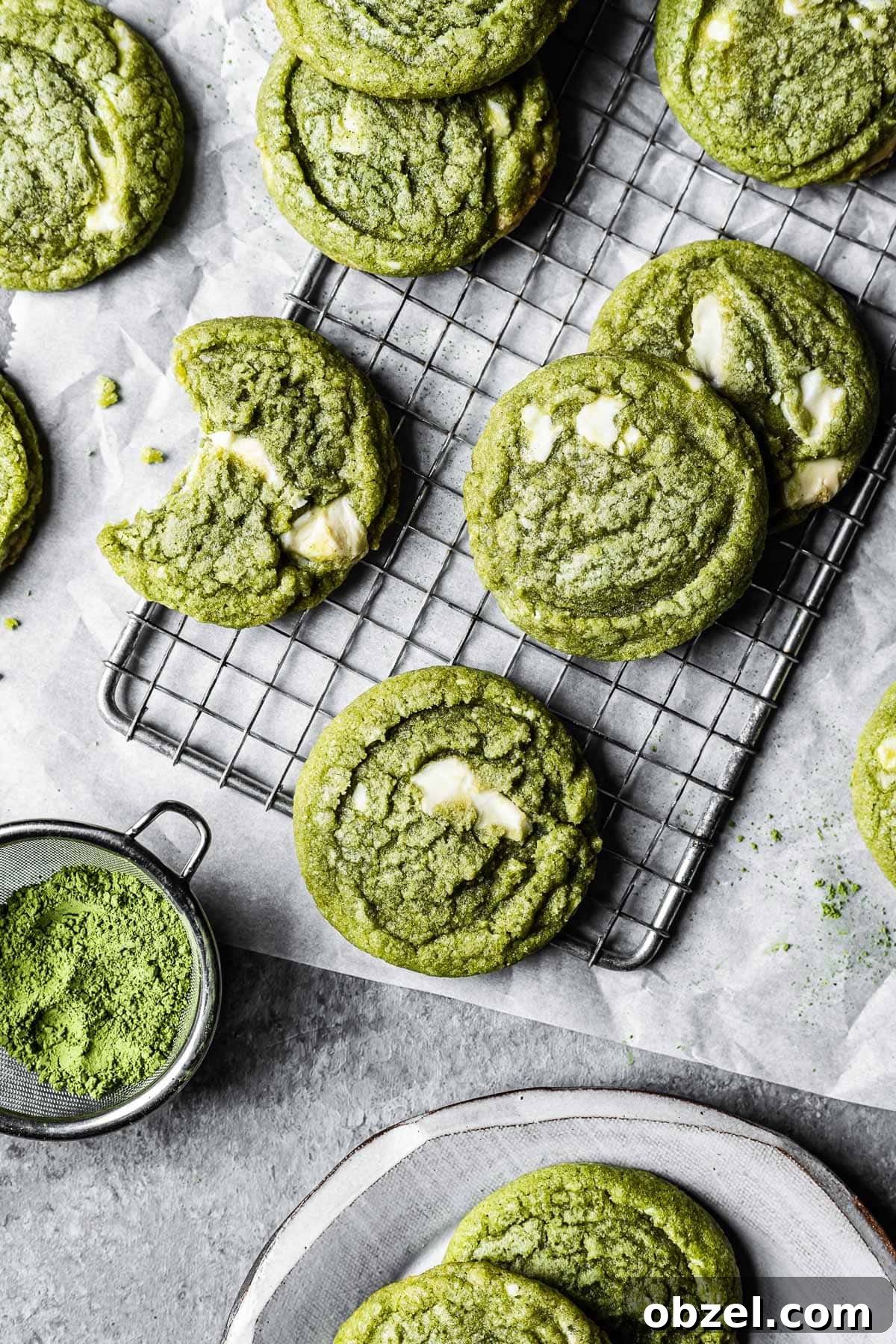 Matcha White Chocolate Cookies Recipe 11 Green matcha white chocolate cookies on a cooling rack resting on white parchment paper.