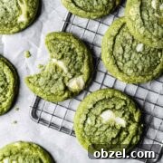 Matcha White Chocolate Cookies Recipe 16 A close up of green drop cookies with white chocolate chunks on a metal cooling rack.