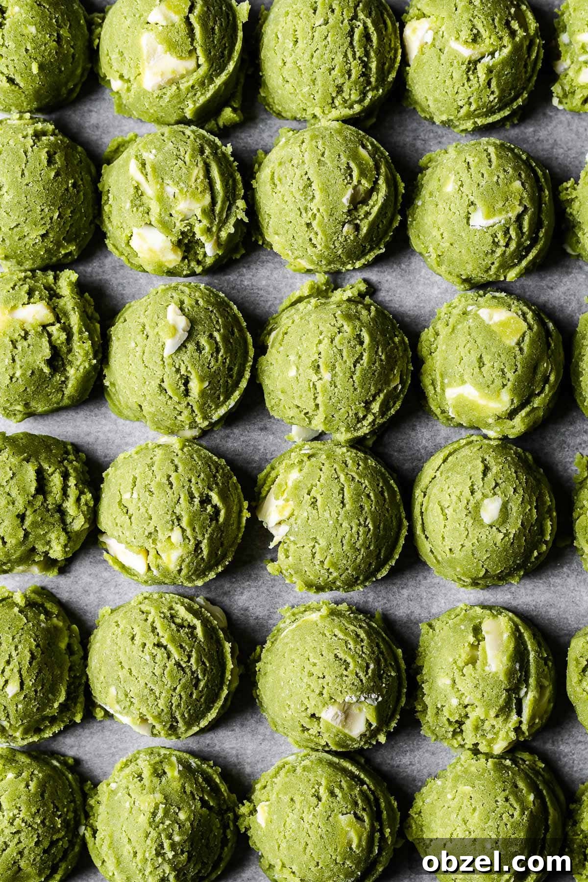Matcha White Chocolate Cookies Recipe 9 Scoops of vibrant green matcha chocolate chip cookie dough lined up in rows.