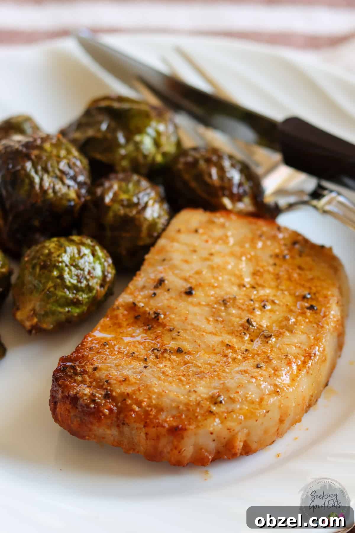 A frozen pork chop that has been cooked in an air fryer served on a white plate.